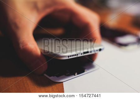 A close-up process of disassemble and dismantle modern mobile phone smartphone with broken shattered display glass and changing details at home