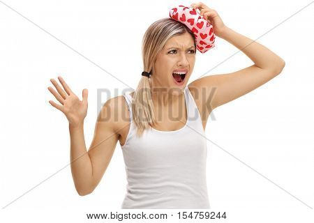 Upset woman experiencing a headache and holding an icepack on her head isolated on white background