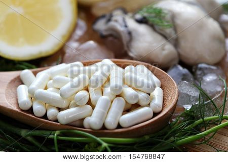 The zinc supplementary white capsule with fresh oyster on block wood