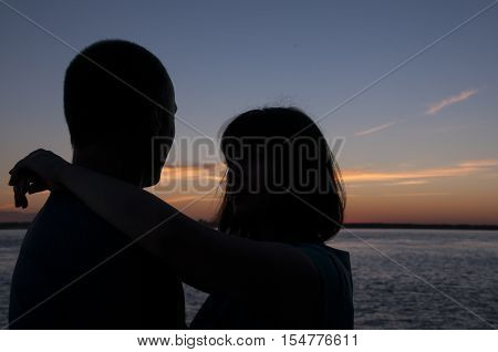 Against the backdrop of the sunset sky male and female silhouette