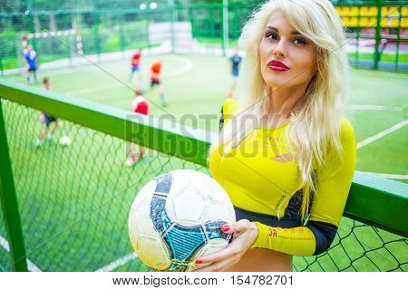 MOSCOW - JUL 16, 2015: beautiful blonde woman (with model release) with ball in hand in top on football field