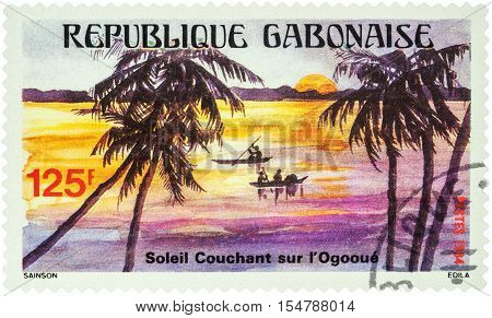 MOSCOW RUSSIA - AUGUST 05 2016: A stamp printed in Gabon shows Evening landscape and canoeing on the tropical Ogooue river series "Tourism" circa 1984