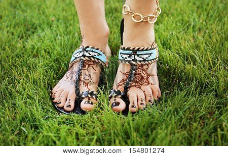 Female legs with henna tattoo on green grass background