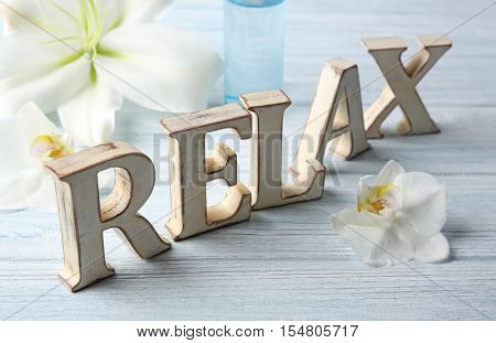 Word RELAX made of letters with flowers on wooden background