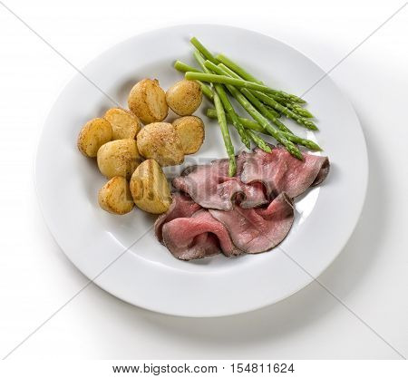 Roast with beef potatoes and asparagus on a white background