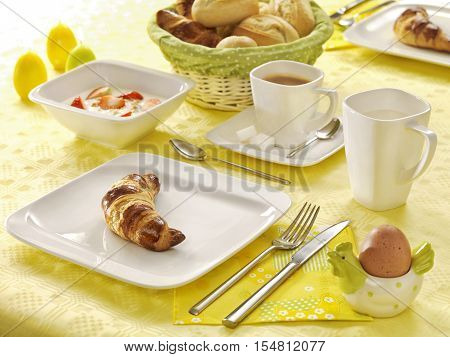 Breakfast table with croissant, eggs, olives, fruit and pastries