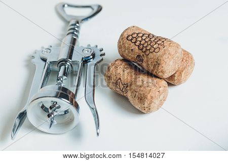 corkscrew and corks lies on a table-top.