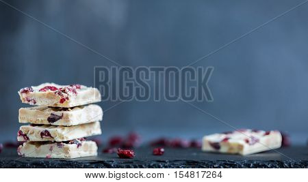Homemade. and tasty white chocolate chunks with cranberries on black slate with copy space