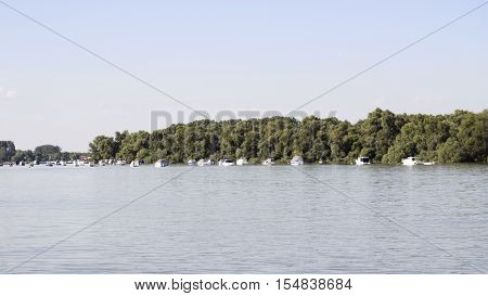Boats anchored on Danube river with beautiful blue sky and trees in background