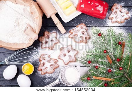 Ingredients for cooking Christmas baking with flour eggs butter and kitchen utensils - rolling pin and whisk. Homemade baked Christmas cookies on wooden background. Christmas background. Top view
