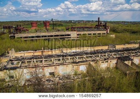 Abandoned factory of synthetic rubber overgrown by trees, ruins of buildings
