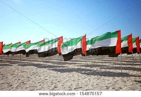 Lot of flags United Arab Emirates for the anniversary celebration on the beach. UAE Natoinal day. Emirates Flag. UAE celebrates National Day on 2nd December every year.