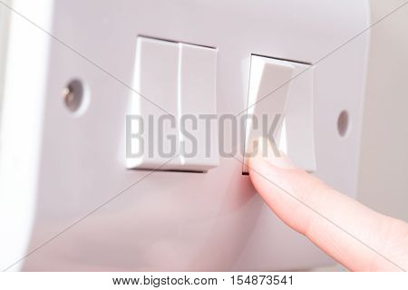 Finger Pushing Light Switch On A 4 Gang Switch Plate