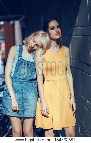 Portrait of two white Caucasian unformal young girls hipster students teenagers friends outside on summer day hugging together best friends forever