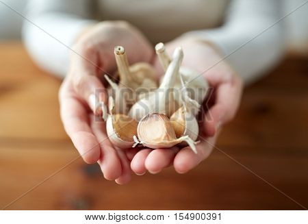 health, people, food, traditional medicine and ethnoscience concept - woman hands holding garlic for cooking or healing