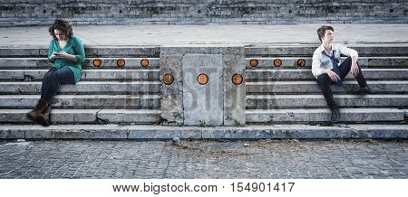 Two teenagers sitting on stairs girl send messages to a boy on smart phone orange dots painted on stairsconcept of communication
