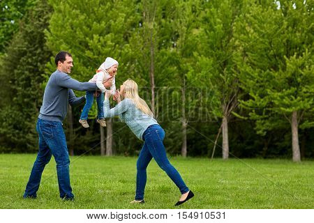 Parents Playing Exciting  With Child In The Park.happy Family.