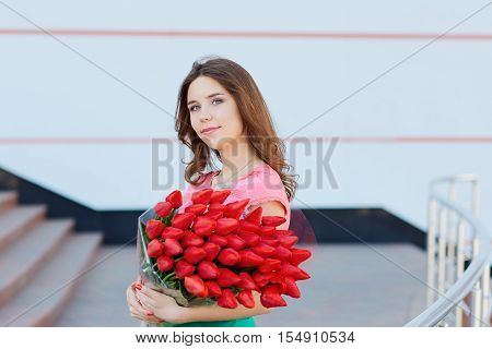 Young Blond Woman With A Bouquet Of Red Tulips.