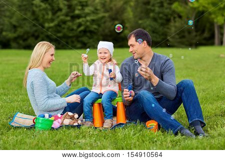 Family playing with bubbles outdoors.Mother dad and child in the park.