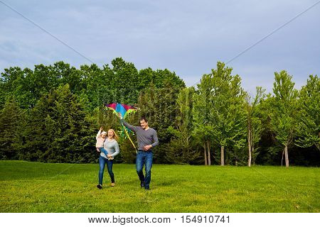 Family with flying kite in park Mother dad and child in the park.