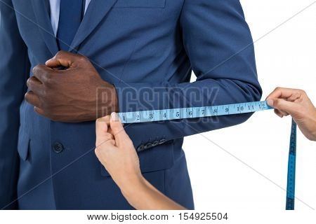 Mid section of woman measuring businessman sleeve on white background