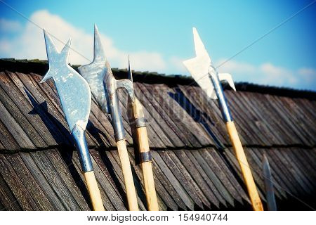 set of middle age style weapons leaning on wooden tiled roof