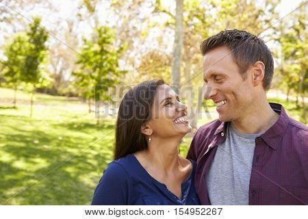 Happy mixed race couple in park looking at each other