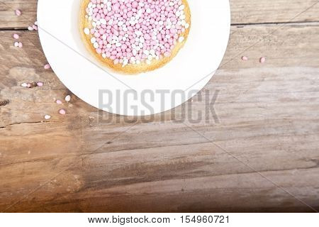 Traditional Dutch birth celebration biscuit with pink muisjes on wooden background