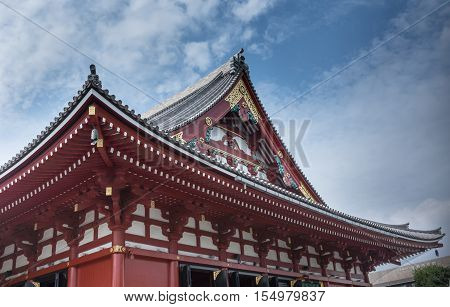 Tokyo Japan - September 26 2016: Part of the highly decorated vermilion roof of the Honzo main hall at Senso-ji Buddhist Temple under blue cloudy sky. Gold metalic decorations.