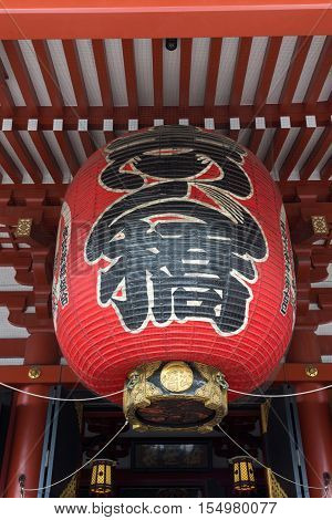 Tokyo Japan - September 26 2016: Giant red paper lantern with black signs at entrance of the main Honzo hall at Senso-ji Buddhist Temple. Vermilion painted wood surrounds.