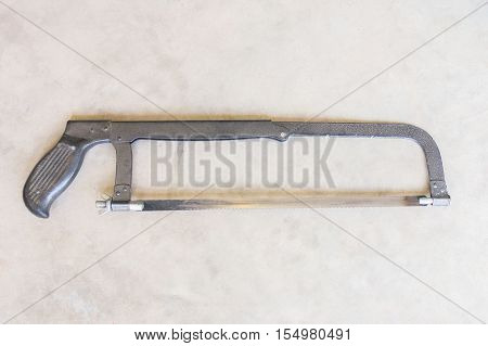 blue hand hack saw tool for metal cut on a wooden background with a copy space for text