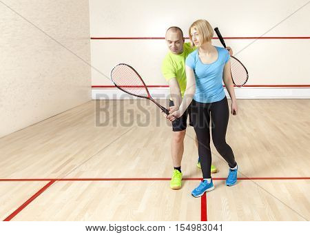 Young Caucasian male coach coaching squash beautiful young blond woman. Horizontal color image