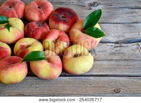 Fresh Organic Chinese Flat Peaches With Leaves On Old Wooden Background.saturn Donut, Doughnut Peach