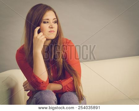 Angry, Pissed Off Young Woman. Attractive Female With Long Brown Hair Sitting On Sofa Being Mad And 