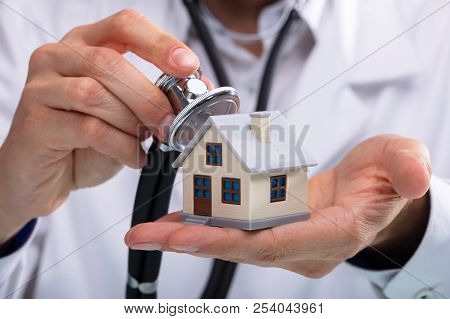 Doctor Examining House Model With Stethoscope