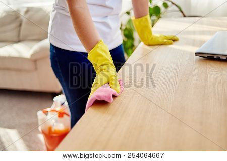 Cropped Image Of Woman's Hand In Yellow Rubber Protective Glove Cleaning Wooden Tablel With Pink Rag