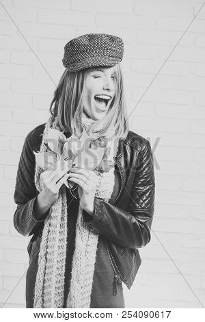 Happy Model With Stylish Hair In Hat. Beauty And Fashion. Girl With Orange Leaves At Brick Wall. Sea
