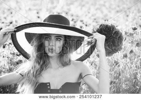 Hat On Retro Girl With Long Curly Hair Hold Red Flower Bouquet In Field Of Poppy Seed On Green Stem 