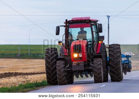 Agricultural Tractor Moving On The Asphalt Road After Working In Field.