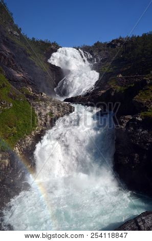 Kjosfossen waterfall flows down valley by the station on the train between Flam and Myrdal in Norway