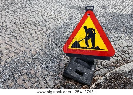 High Angel View Of A Triangle Shaped Temporary Roadwork Warning Sign Placed On A Street Paved With C