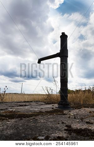 Old Pump With Dry Soil, Dramatic Cloudy Sky, Water Shortage