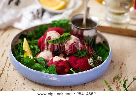 Beet Falafel With Tahina  Sauce And Green . Salad Selective Focus