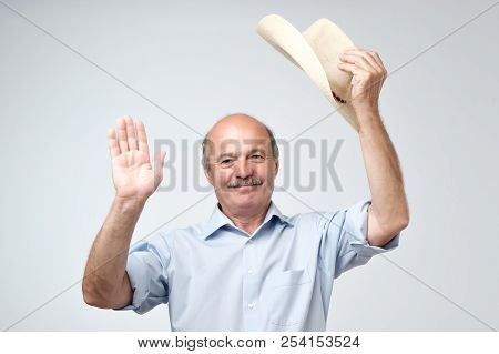Portrait Of A Smiling Mature European Man Putting Cowboy Hat Off And Looking At Camera. I Am Waiting