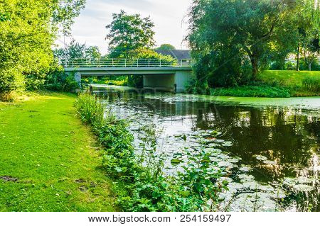 Water Landscape With A River, Bridge And Grass Lawn