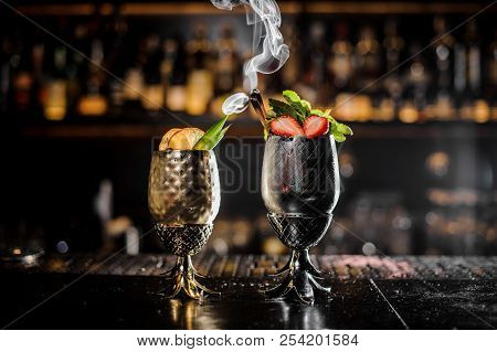 Metal Glasses Of Fresh Summer Cocktails Decorated With Fruit And Fume On The Bar Counter