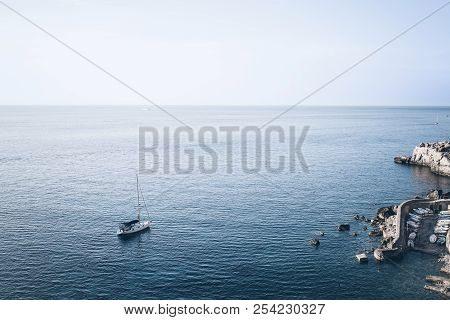 High Angle View Of Small Harbor And Sailboat Against Blue Sea And Sky