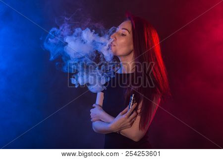 Portrait Of Asian Woman Smoking Vape Or E-cigarette In Neon Light At Black Background.