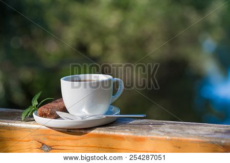 Cup Of Hot Coffee For Brackfast  On Wooden Balcony Near River And Mountain Background