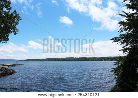 View Of Canandaigua Lake From The Bridge. Calm Water And Blue Sky With White Clouds. Finger Lakes In
